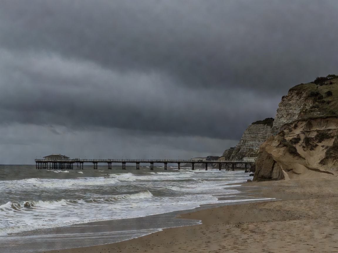 Bournemouth Pier and sandy cliffs under a heavy overcast sky