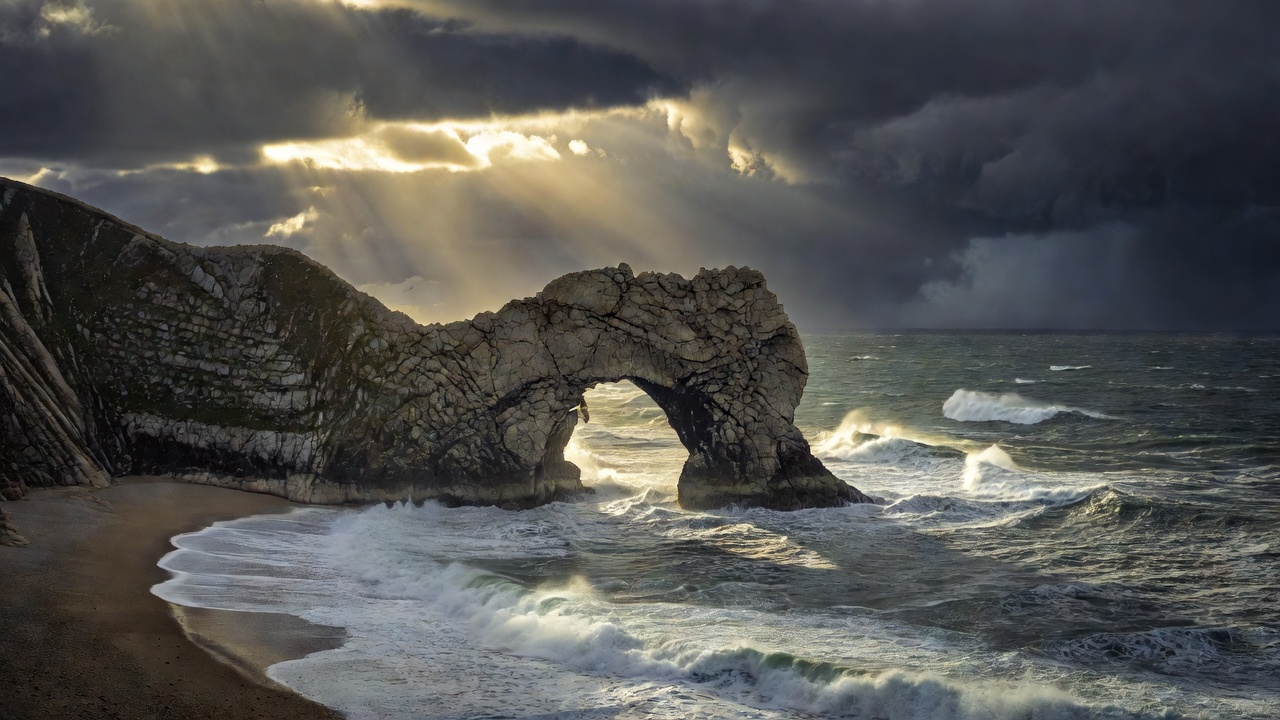 The limestone arch of Durdle Door on the Jurassic Coast under dramatic storm light